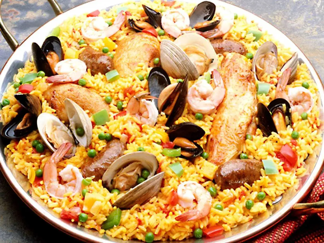 En stor paella med ris, räkor, musslor, kyckling och grönsaker. Ett perfekt paella recept för en festmåltid.
