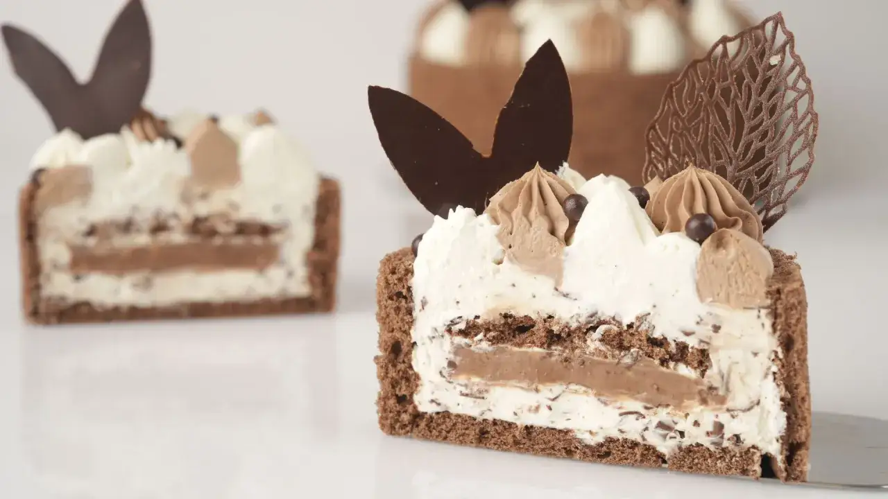 Une tranche de charlotte au chocolat, garnie de cr&egrave;me fouett&eacute;e, de copeaux de chocolat et de billes croquantes. Un d&eacute;lice pour les yeux et les papilles.