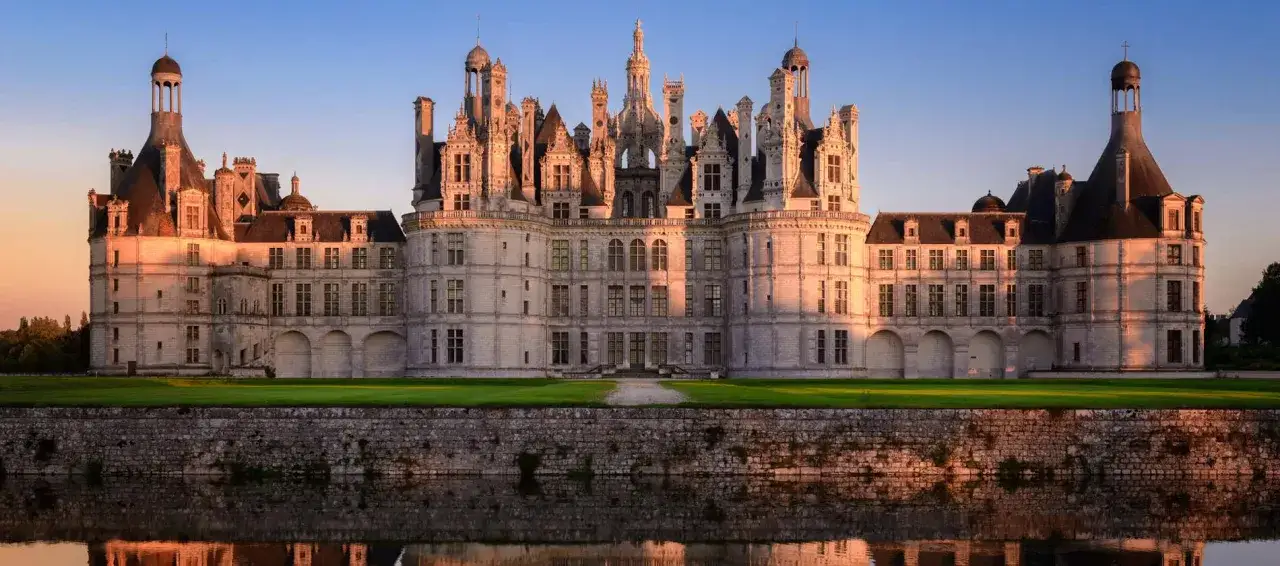 Le ch&acirc;teau de Chambord, un des plus c&eacute;l&egrave;bres ch&acirc;teaux en France, se refl&egrave;te dans l'eau au coucher du soleil.