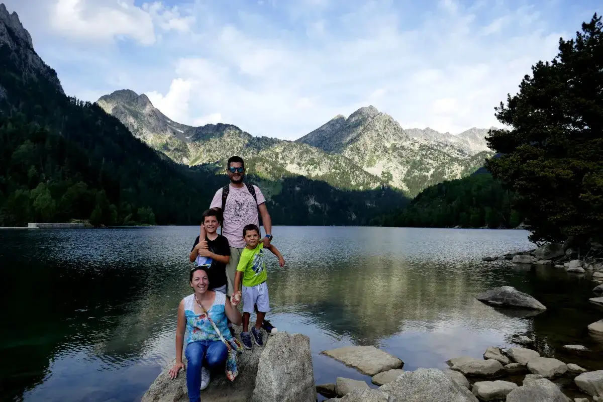 Familia feliz en un lago rodeado de monta&ntilde;as, ideal para conocer gente para viajar y compartir aventuras.