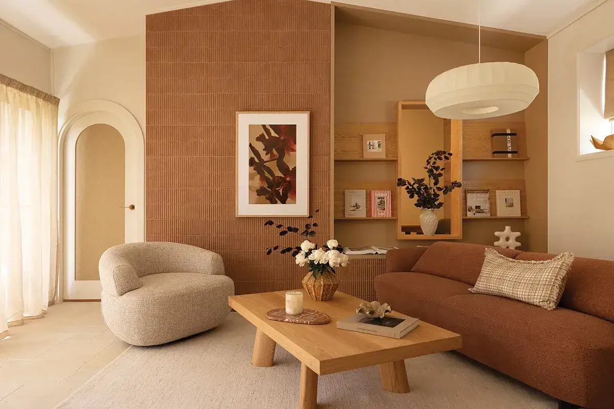 Gemütliches Wohnzimmer mit organischen Formen und warmen Erdtönen. Ein geschwungener Sessel und ein braunes Sofa laden zum Entspannen ein. Das moderne **interior design** besticht durch Texturen und natürliche Materialien.