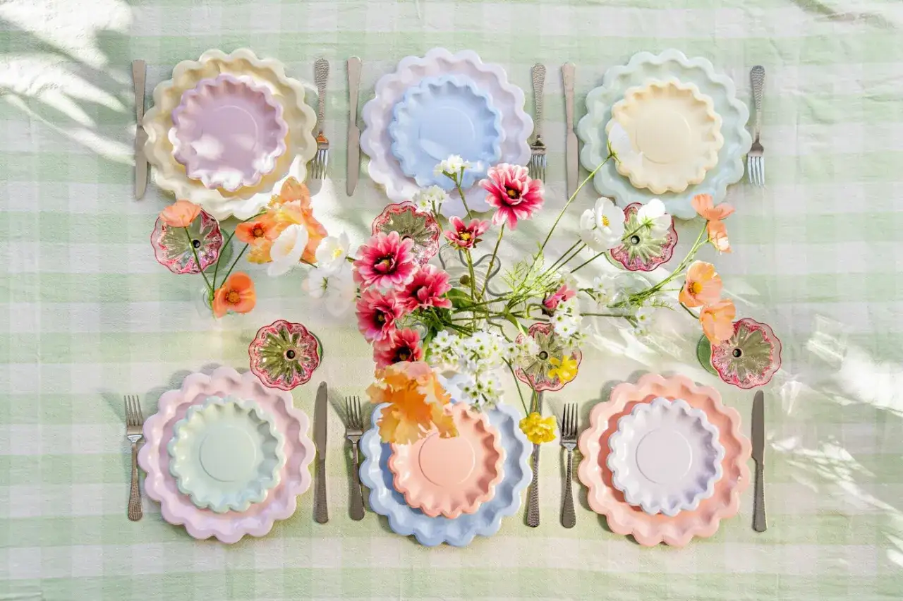 Vackert dukat bord med pastellfärgade tallrikar och blommor. Perfekt för roliga smaktester och en härlig stund.