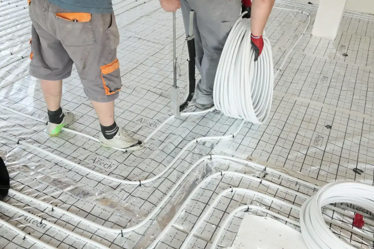 Instalatorzy układają rury do ogrzewania podłogowego. Dowiedz się, ile kosztuje ogrzewanie podłogowe i jakie są jego zalety.