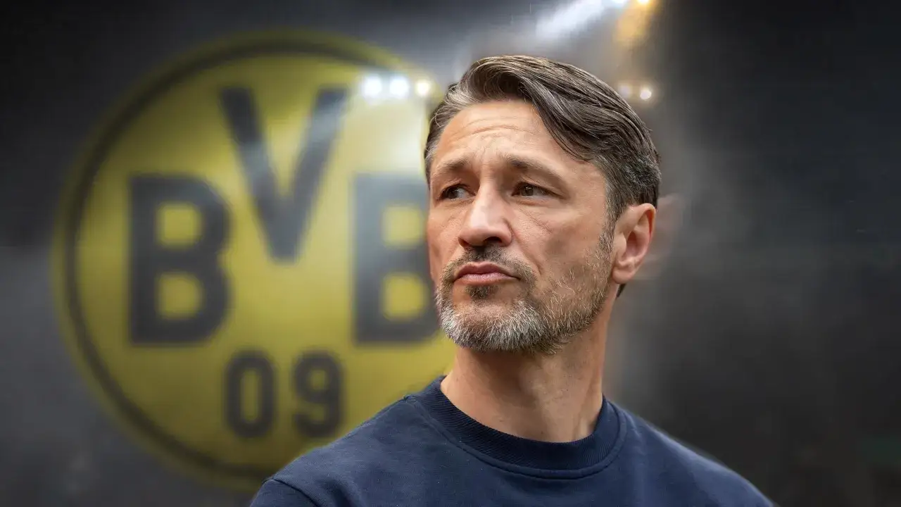 Kovac trener, zamyślony, na tle logo BVB.