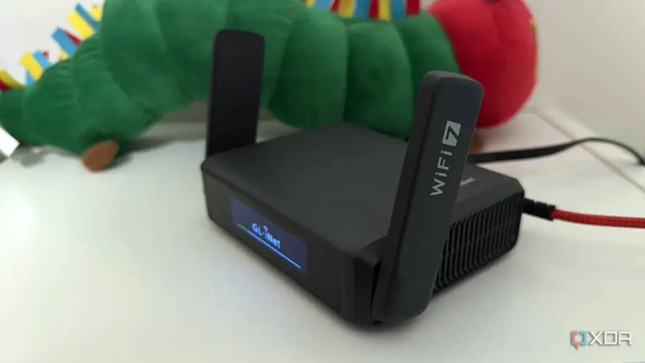 Router z oznaczeniem WiFi 7, gotowy do pracy, obok pluszowej gąsienicy.