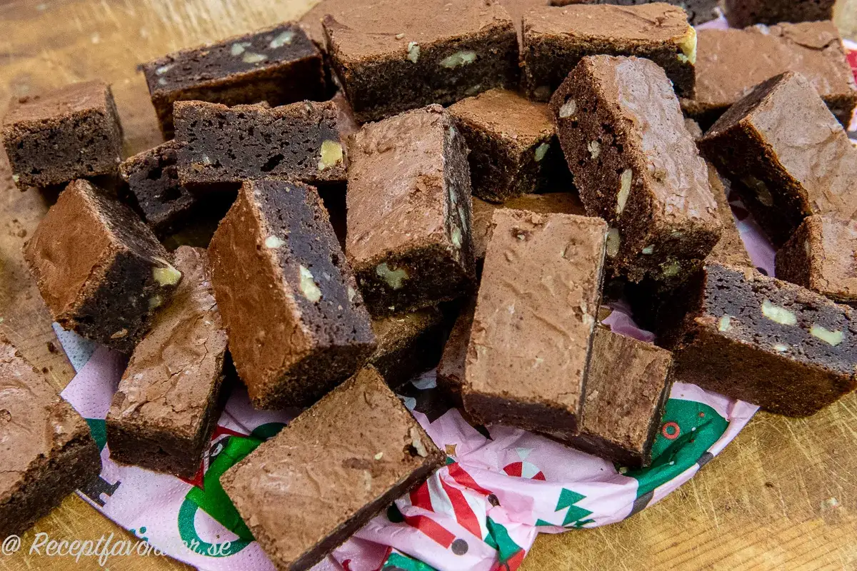 En hög med fudgiga brownies, bakade i långpanna, med synliga bitar av nötter. Perfekt för fikat!