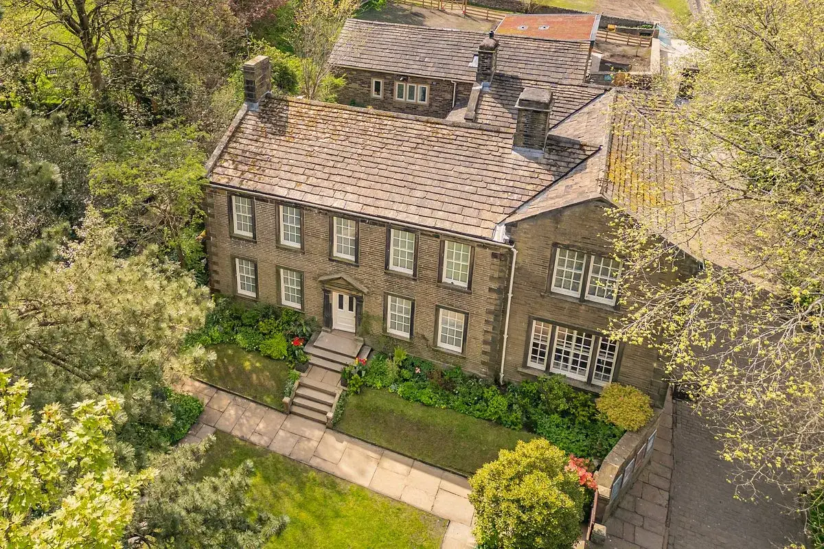 La maison o&ugrave; les s&oelig;urs Bront&euml; ont &eacute;crit leur histoire, entour&eacute;e de verdure et d'arbres fleuris.