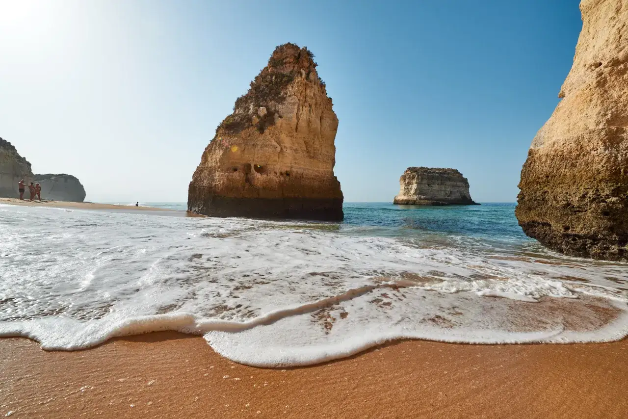Felsformationen am Strand von Praia da Marinha, ein Muss in Portugal. Wellen brechen sanft am goldenen Sand.