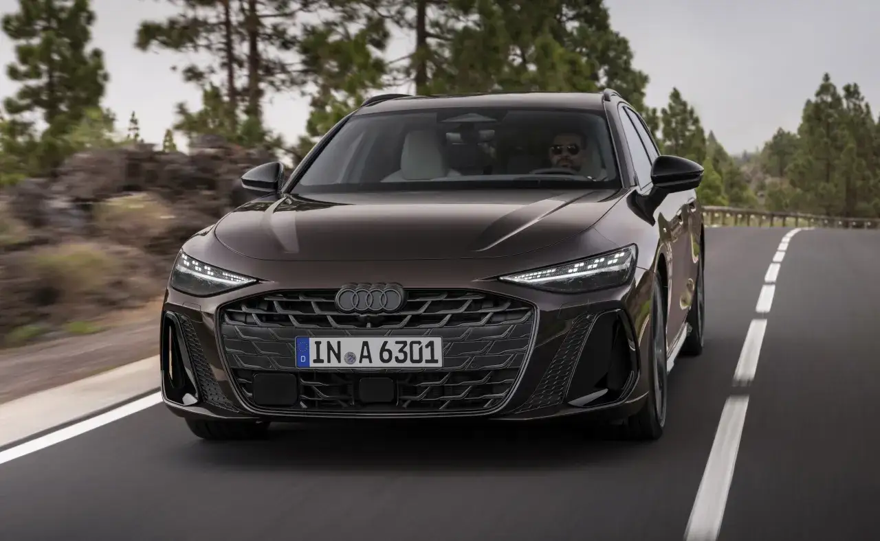Eleganckie audi hybryda w kolorze brązowym jedzie po krętej drodze wśród drzew.