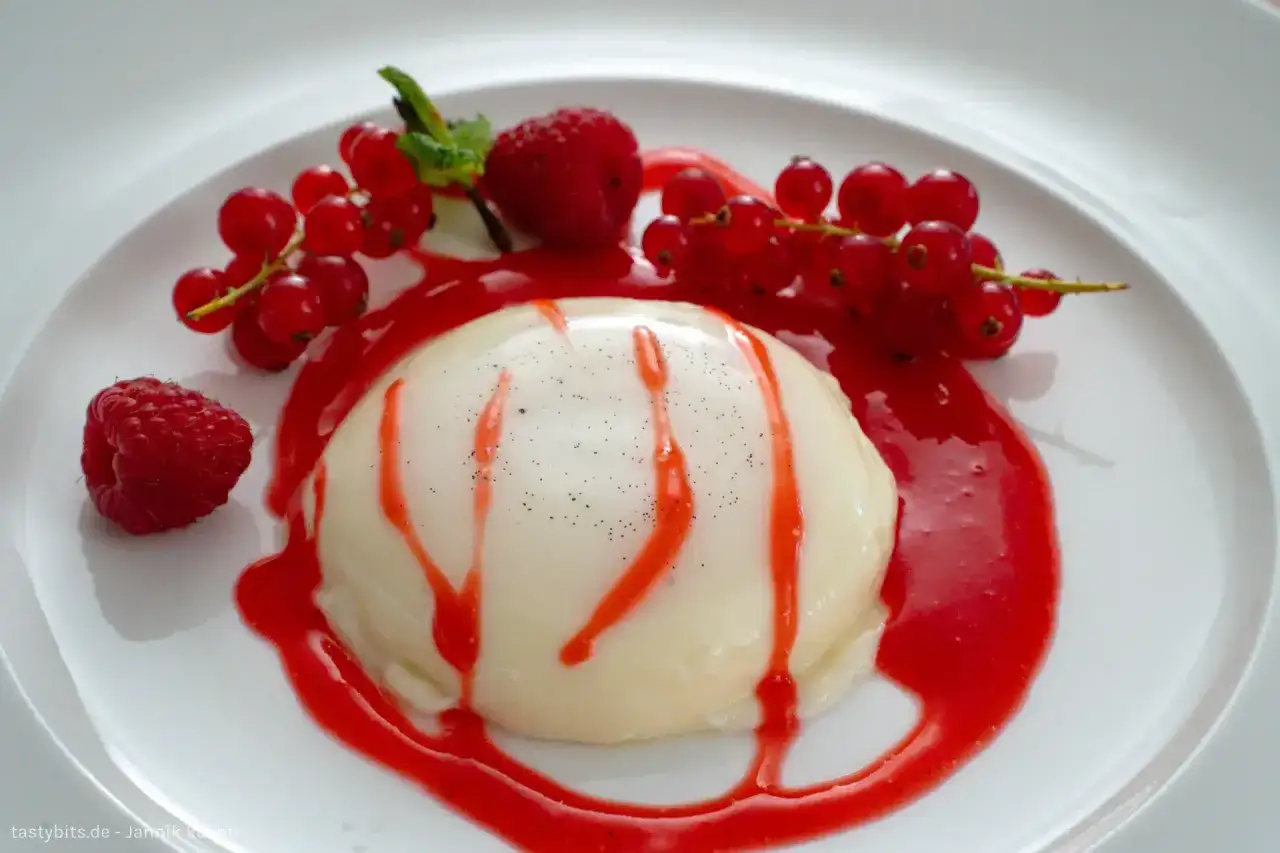 Cremige Panna Cotta mit roter Fruchtsauce, Johannisbeeren und einer Himbeere. Ein s&uuml;&szlig;er Genuss!