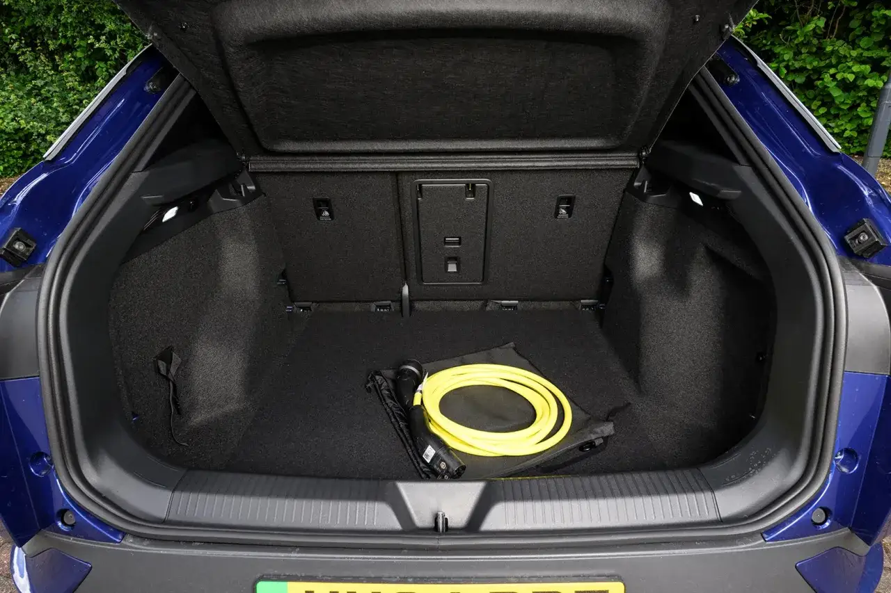 Błękitny VW ID.4 z otwartym bagażnikiem, w którym leży żółty kabel do ładowania.