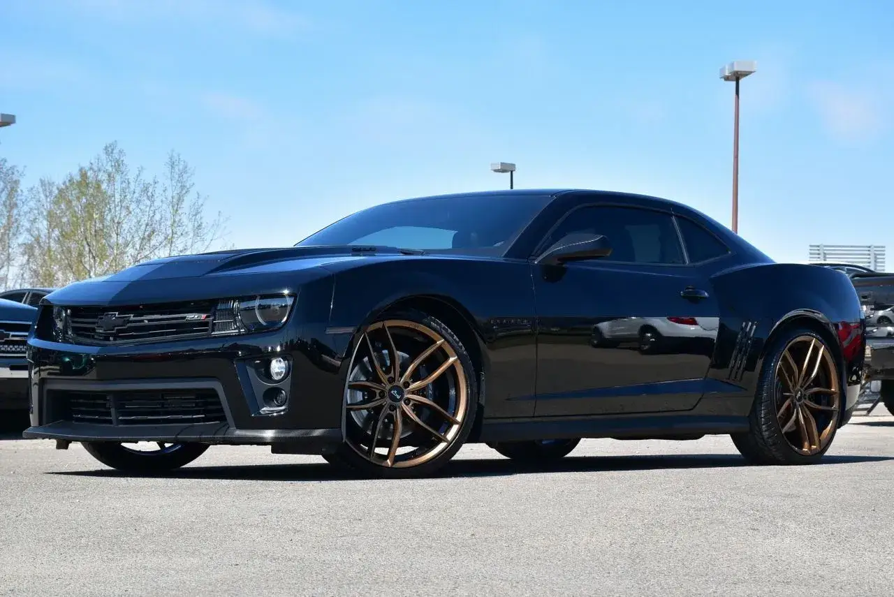 Czarny Camaro ZL1 z brązowymi felgami, gotowy do jazdy po asfalcie.