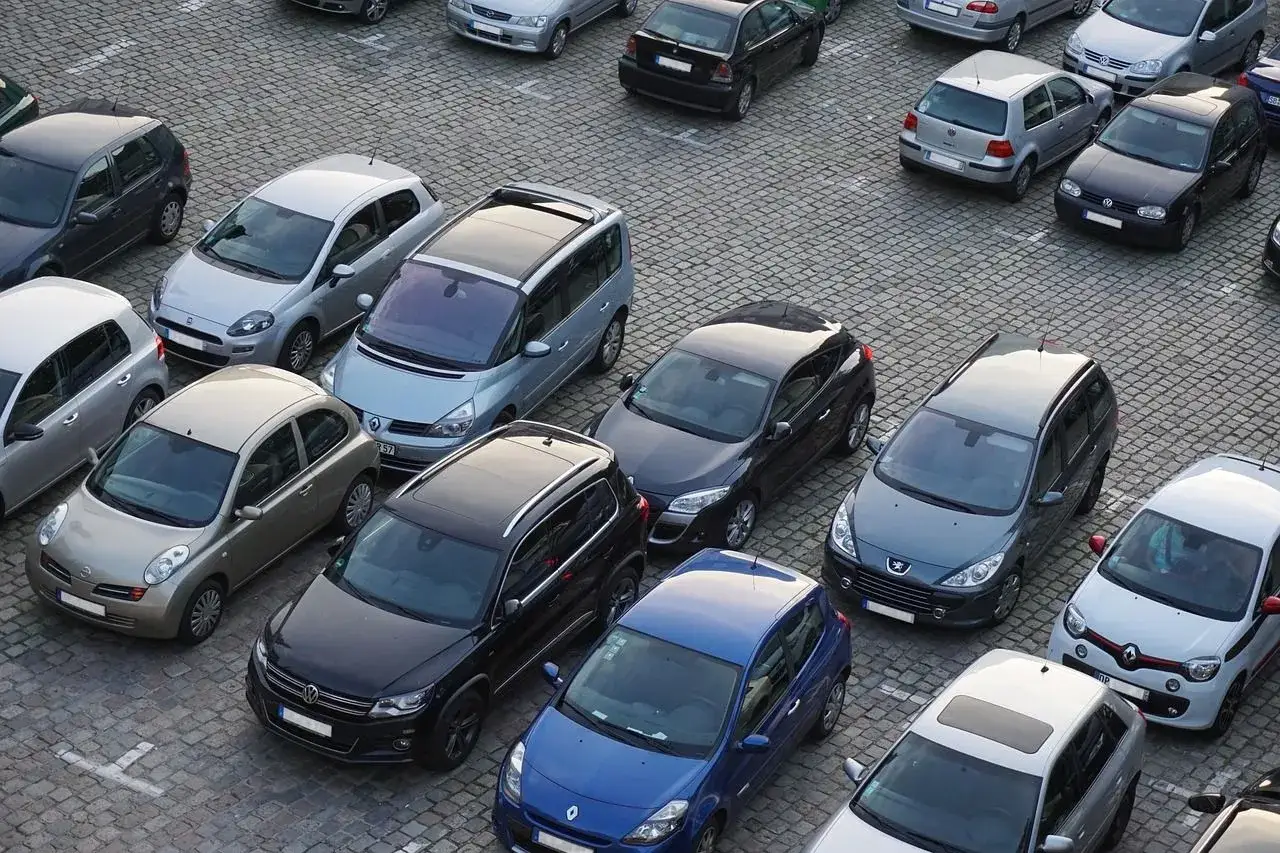 Wiele samochodów na brukowanym placu, który służy jako prywatne miejsce parkingowe pod blokiem.