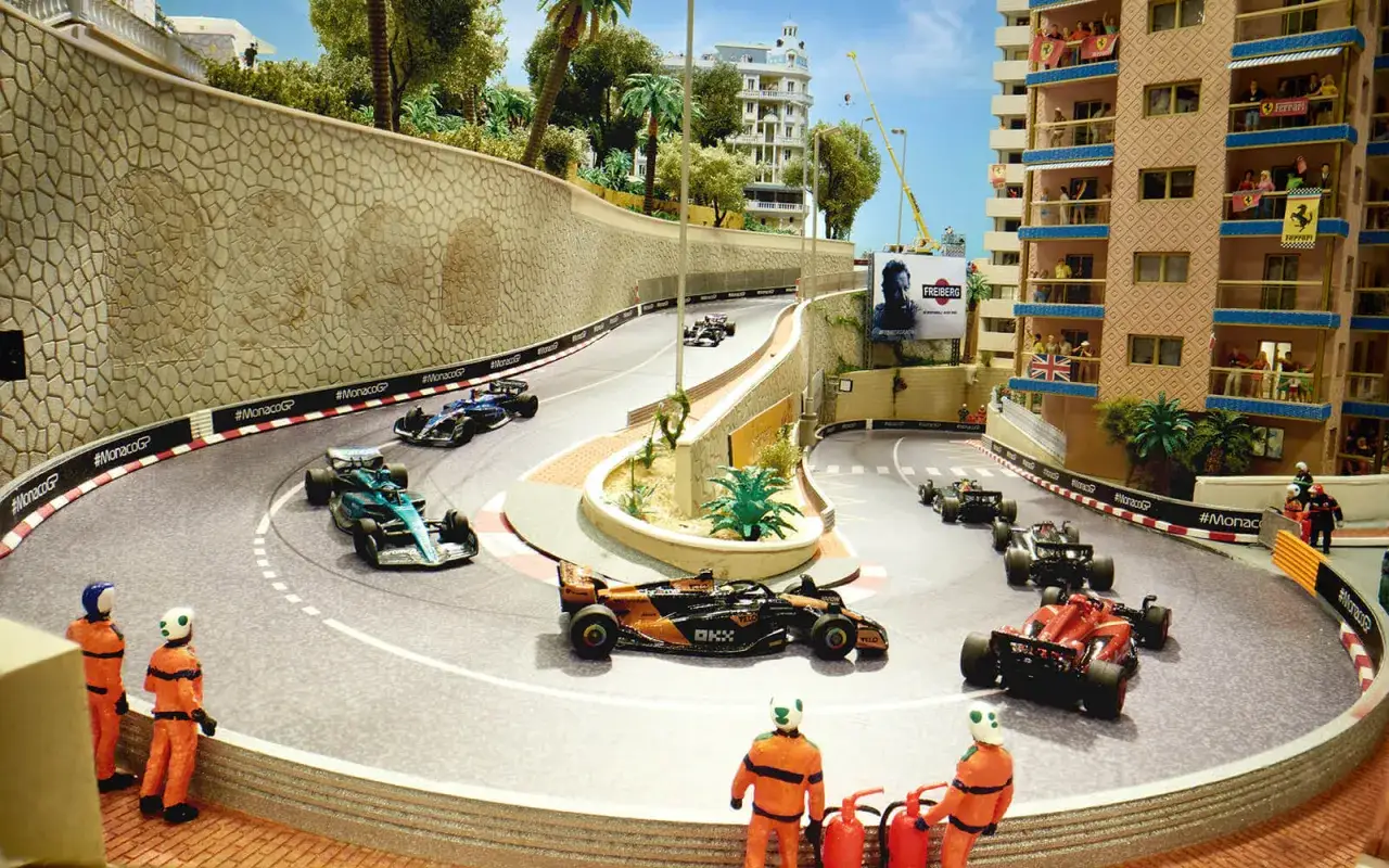 Miniatur-Rennstrecke mit Formel-1-Autos, die den gro&szlig;en Preis von Monaco nachstellen. Zuschauer auf Balkonen jubeln.