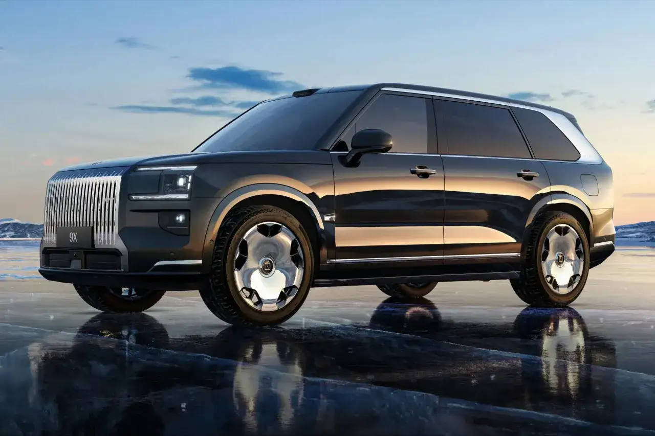 Elegancki, ciemny SUV Zeekr 9X z chromowanymi felgami stoi na lodzie, odbijając się w tafli.