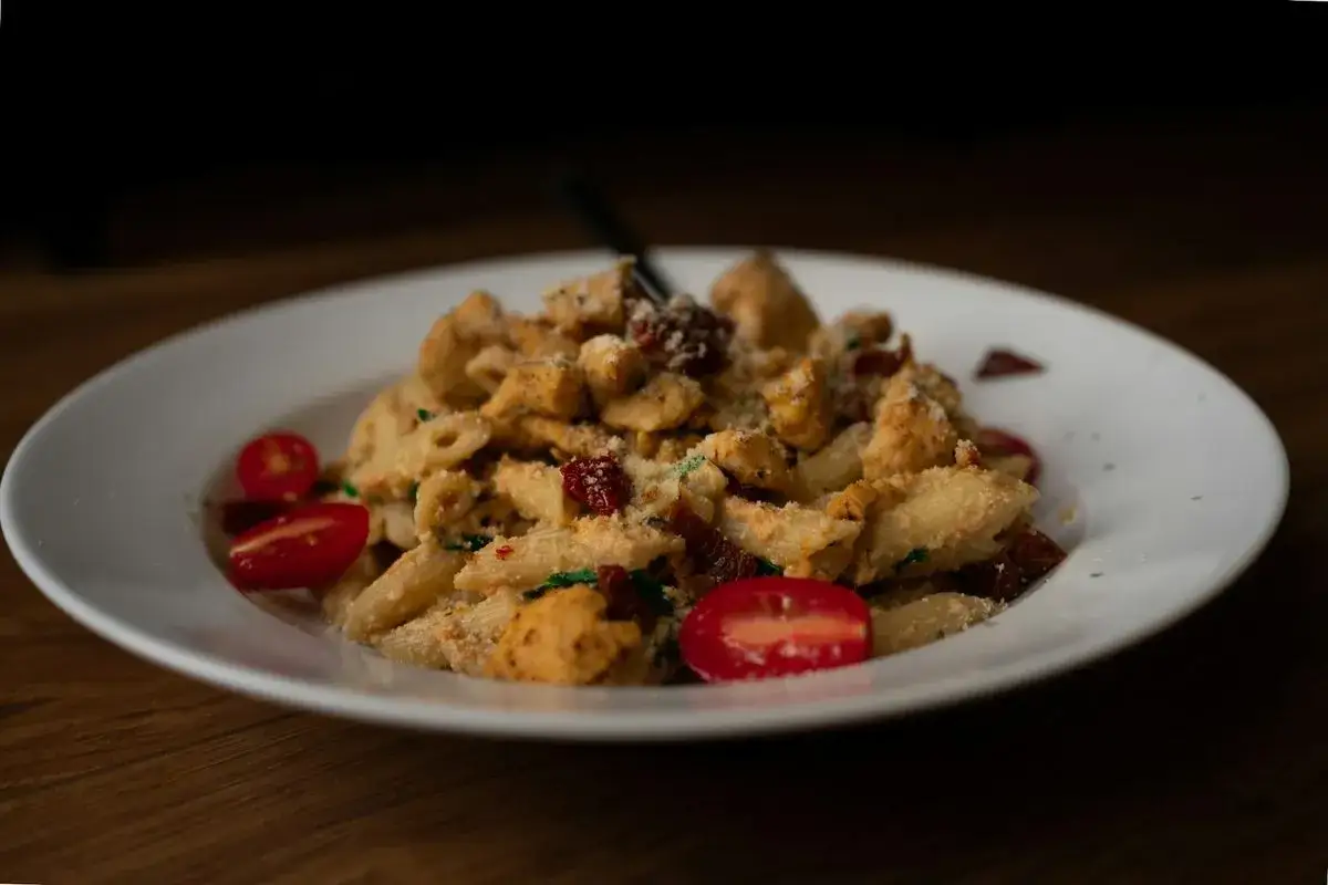 Penne z kurczakiem i suszonymi pomidorami, posypane parmezanem. Aromatyczne danie, które zachwyci każdego smakosza.