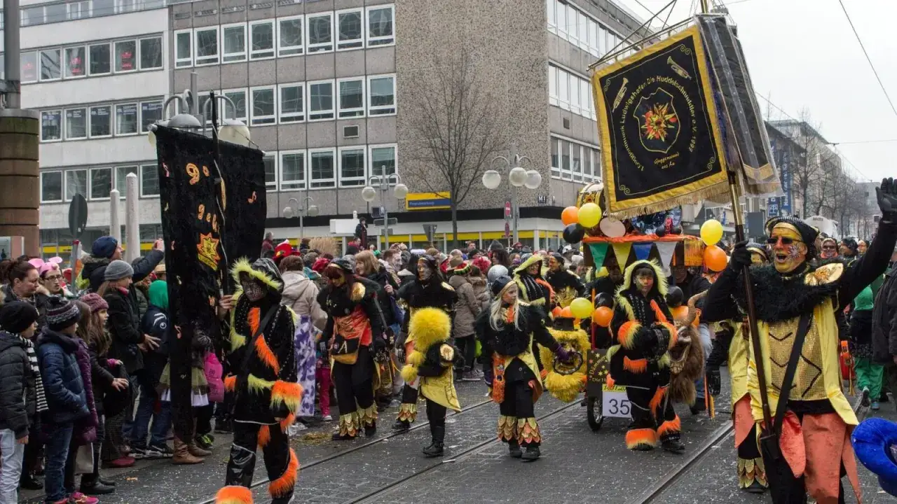 Bunte Kostüme und fröhliche Gesichter – so feiert man Fasching! Eine Gruppe zieht mit Musik und Fahnen durch die Stadt.