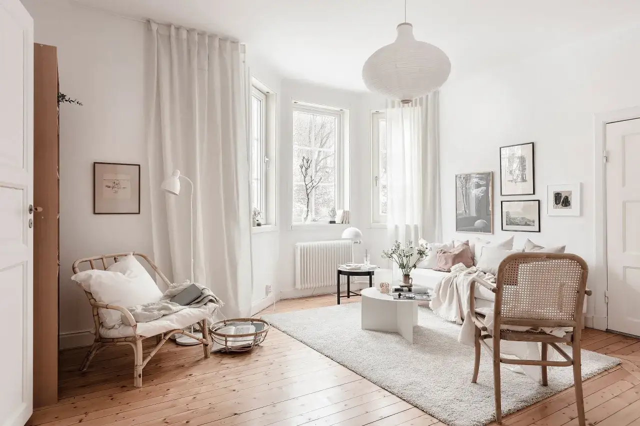 Acogedor salón de **piso 25 metros cuadrados**, con muebles de ratán, sofá blanco y mucha luz natural.