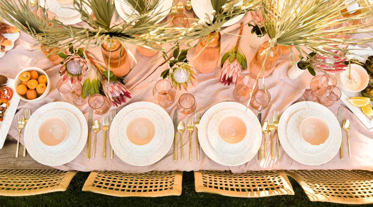 Un magnifique ensemble de vaisselle aux motifs g&eacute;om&eacute;triques, avec des assiettes, des bols et des couverts dor&eacute;s, pr&ecirc;t pour un repas en plein air.
