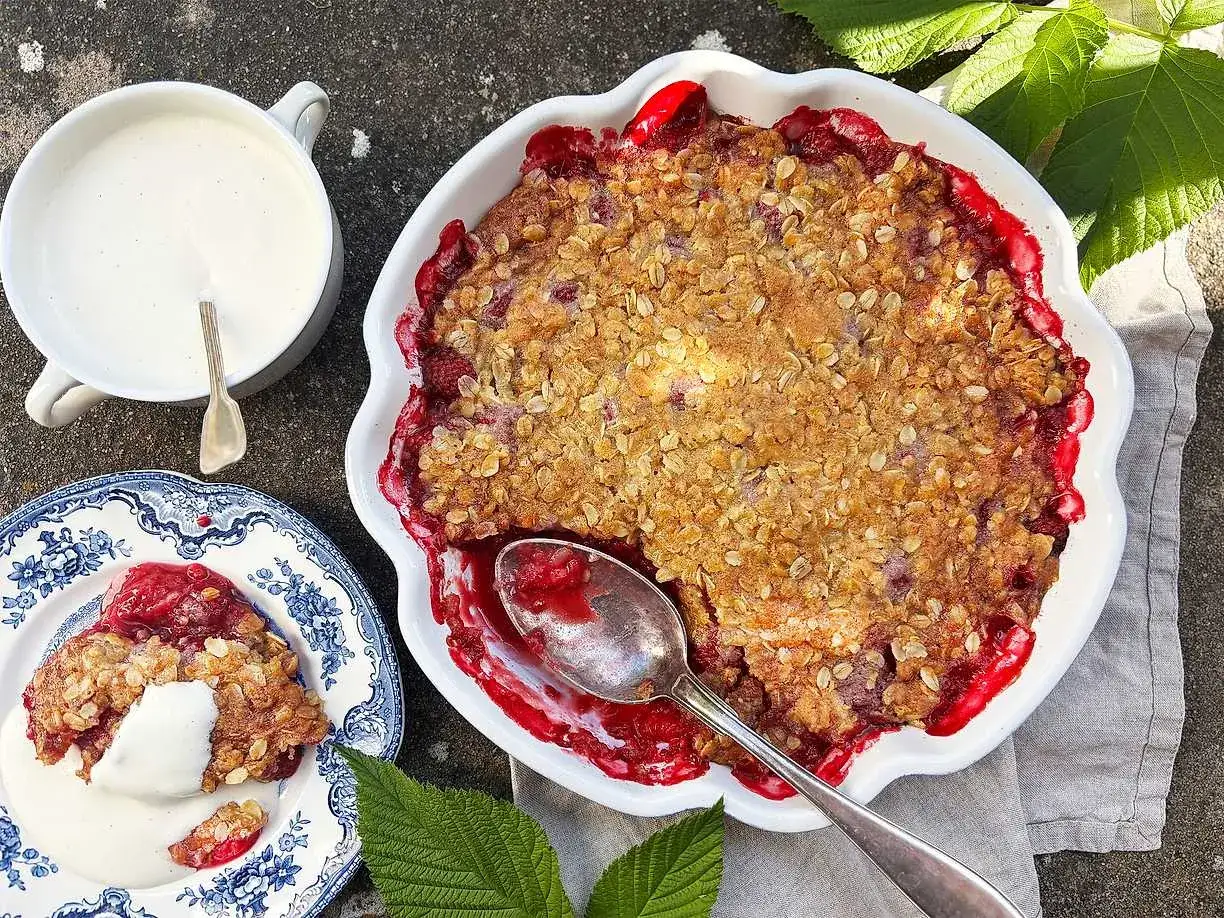 En härlig hallonpaj med krispigt täcke, serverad med vaniljsås. Perfekt för ett sommarfika.