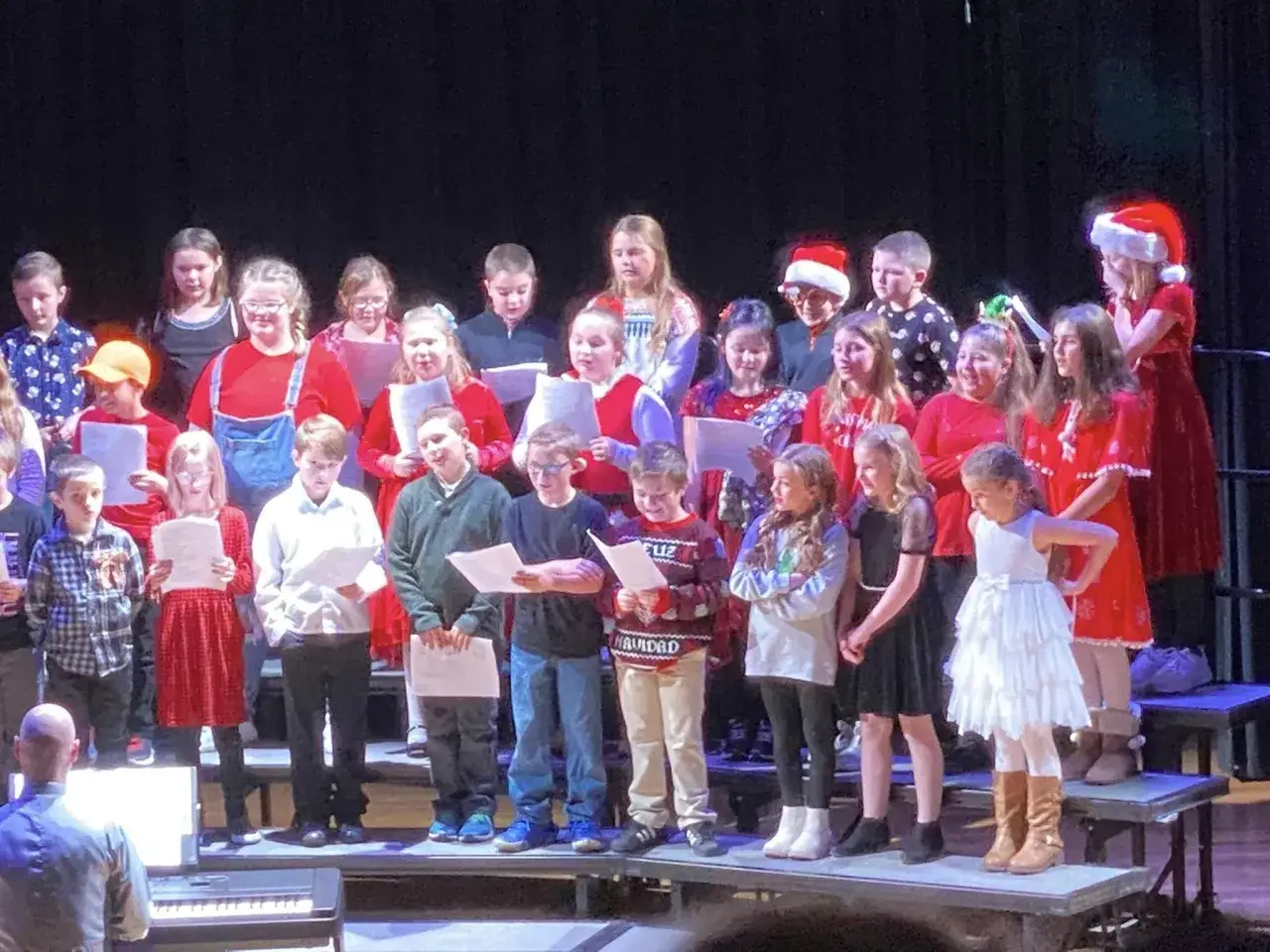 Un coro de niños canta canciones sobre el invierno, algunos con gorros de Papá Noel.