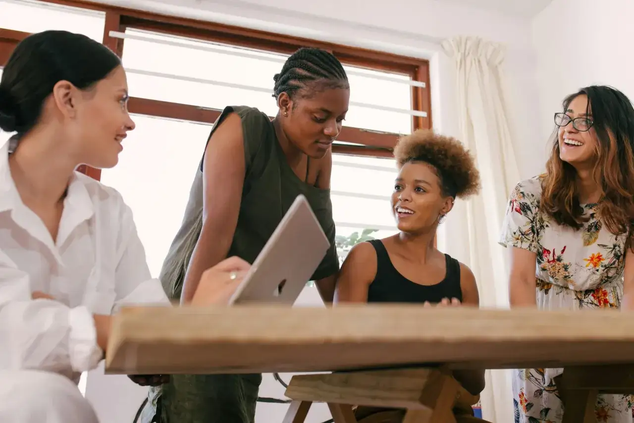 Four women collaborate, their engaged expressions and shared focus highlighting their strong relational capacity as they discuss a project.