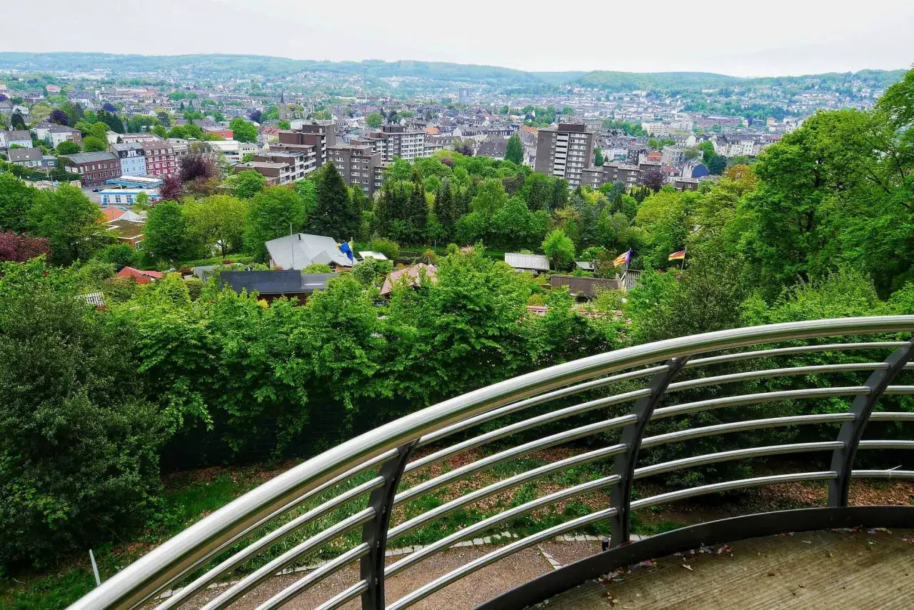 Blick &uuml;ber den gr&uuml;nen **Nordpark Wuppertal** mit H&auml;usern und B&auml;umen. Im Hintergrund die Stadt und H&uuml;gel.