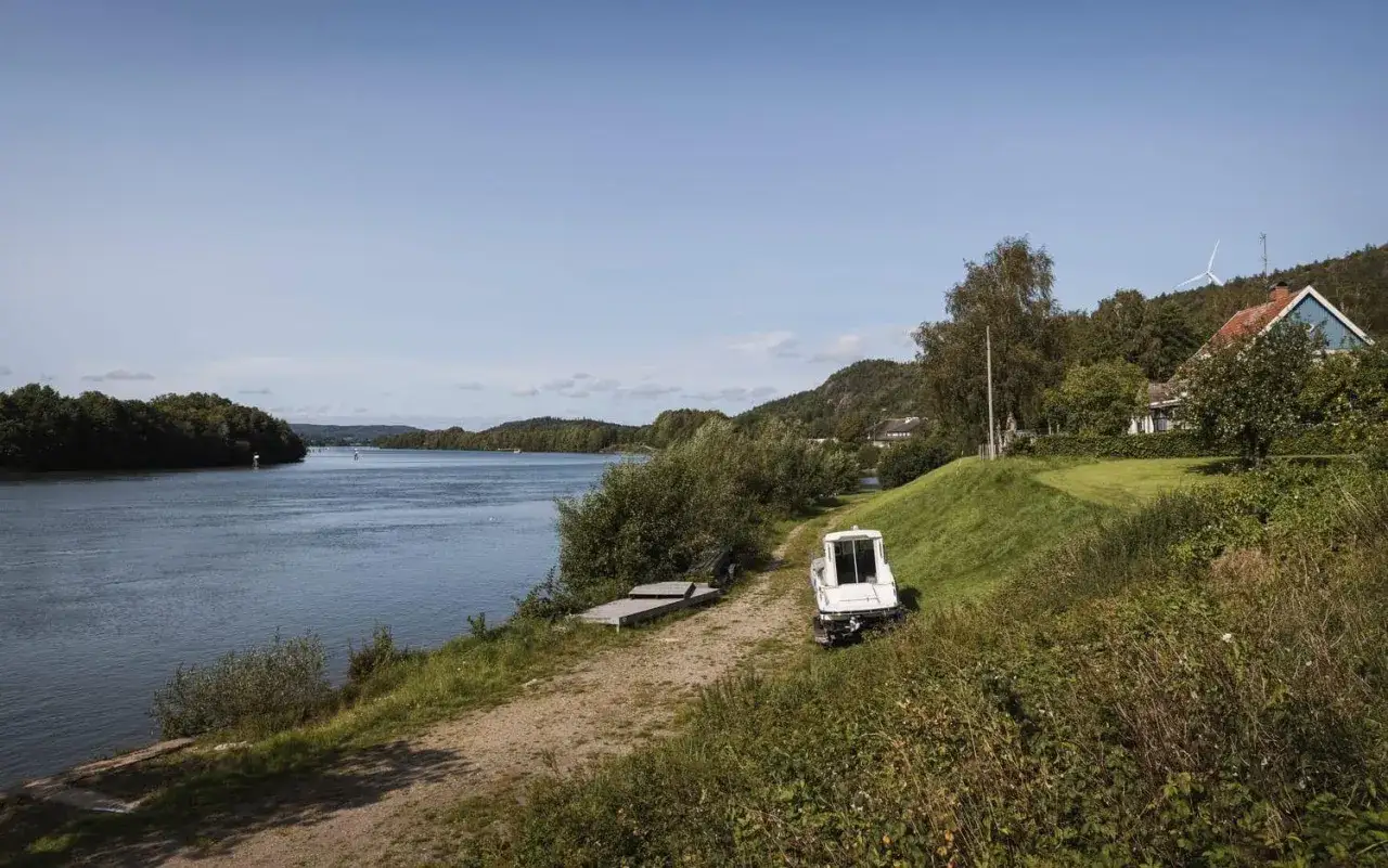 En vacker dag vid vattnet n&auml;ra camping Lilla Edet. En vit b&aring;t st&aring;r parkerad vid en grusv&auml;g, redo f&ouml;r &auml;ventyr p&aring; sj&ouml;n.