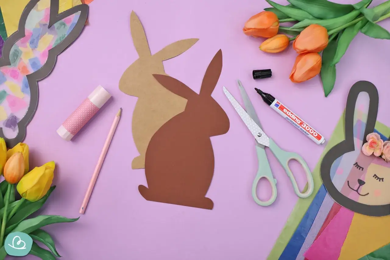 Bastelmaterialien f&uuml;r einen Osterhasen aus Tonpapier: Schere, Stift, Kleber, Papierhasen-Vorlage und bunte Tulpen.