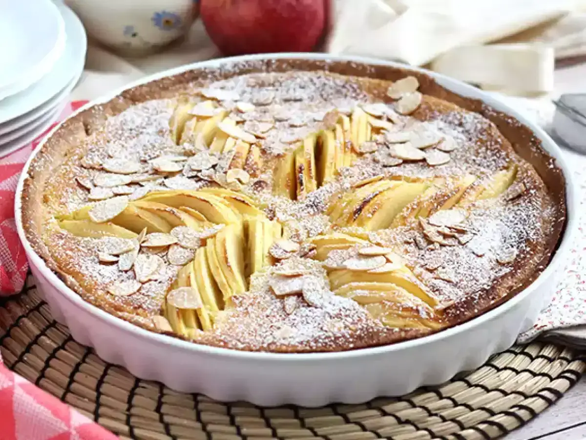 Tarte normande aux pommes, saupoudr&eacute;e de sucre glace et d'amandes effil&eacute;es, pr&ecirc;te &agrave; &ecirc;tre d&eacute;gust&eacute;e.