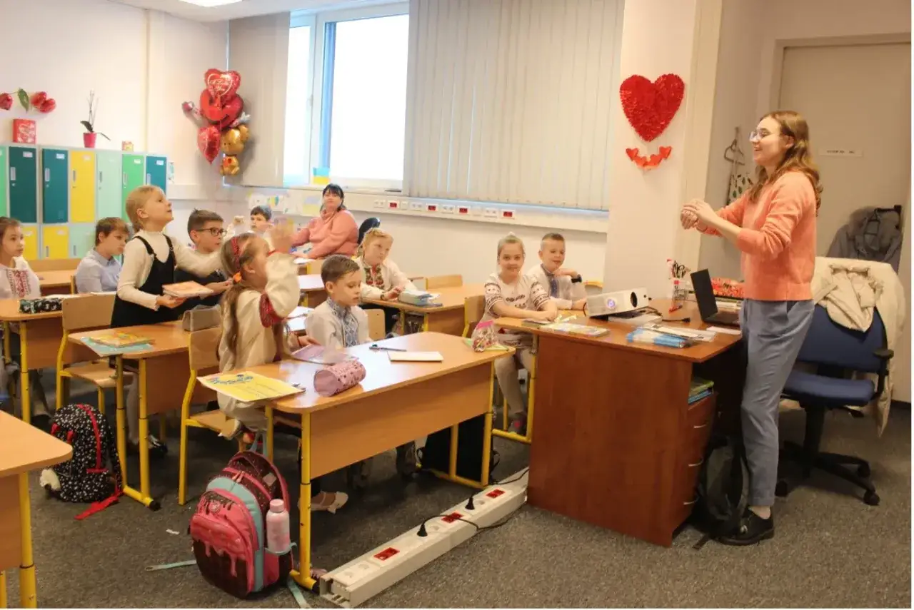 Dzieci w klasie, uczące się z nauczycielem. Idealne miejsce, gdzie wysłać dziecko na obóz językowy, by rozwijało swoje pasje.