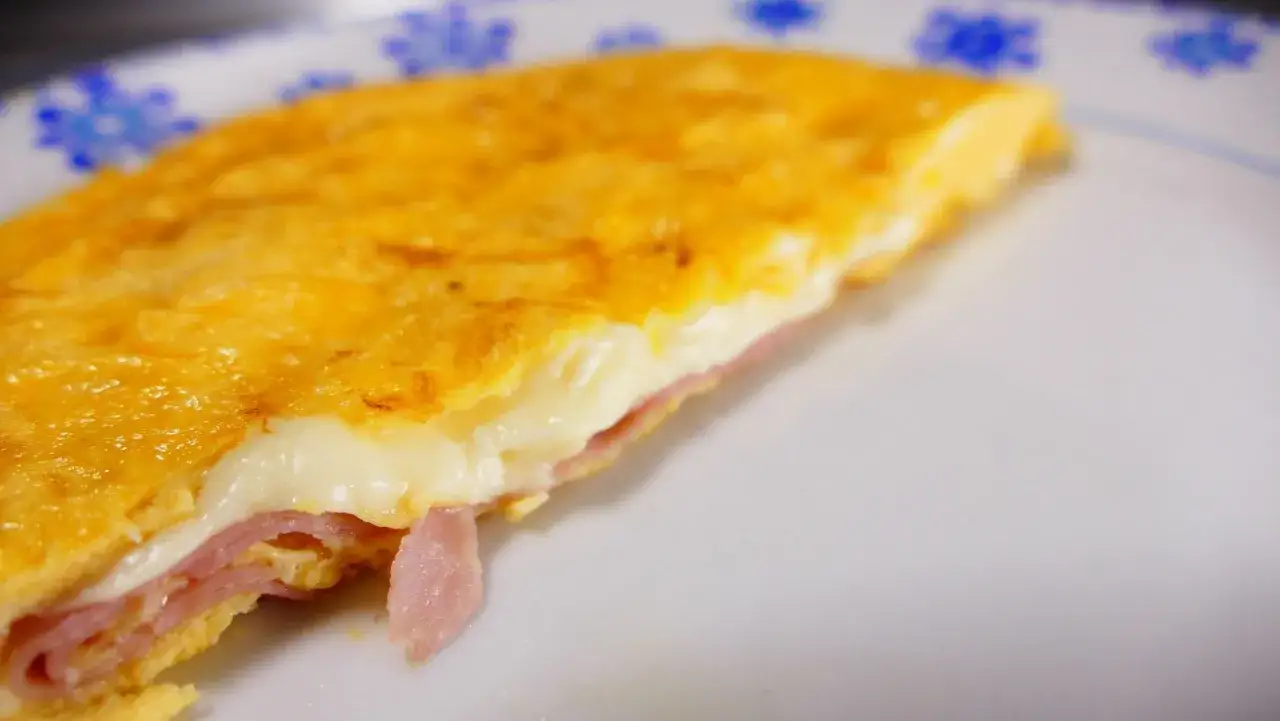 Tortilla francesa rellena de jam&oacute;n y queso fundido, un bocado delicioso y reconfortante.