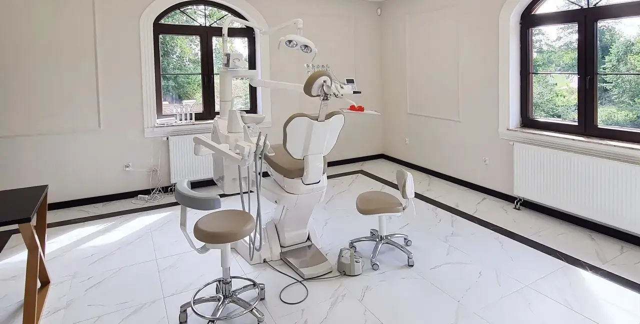 Nowoczesny gabinet stomatologiczny z fotelem, unitem i krzesłami.