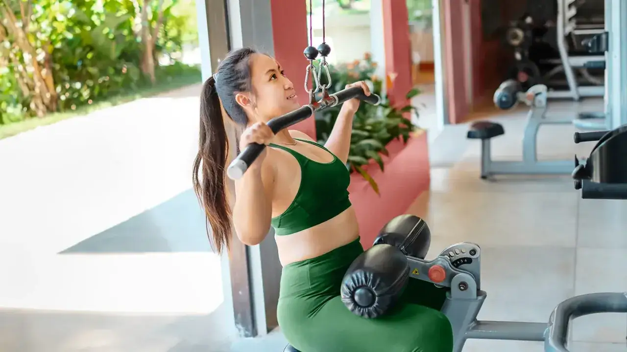 Donna in palestra esegue lat machine, un esercizio chiave per chi vuole imparare come mettere massa muscolare.
