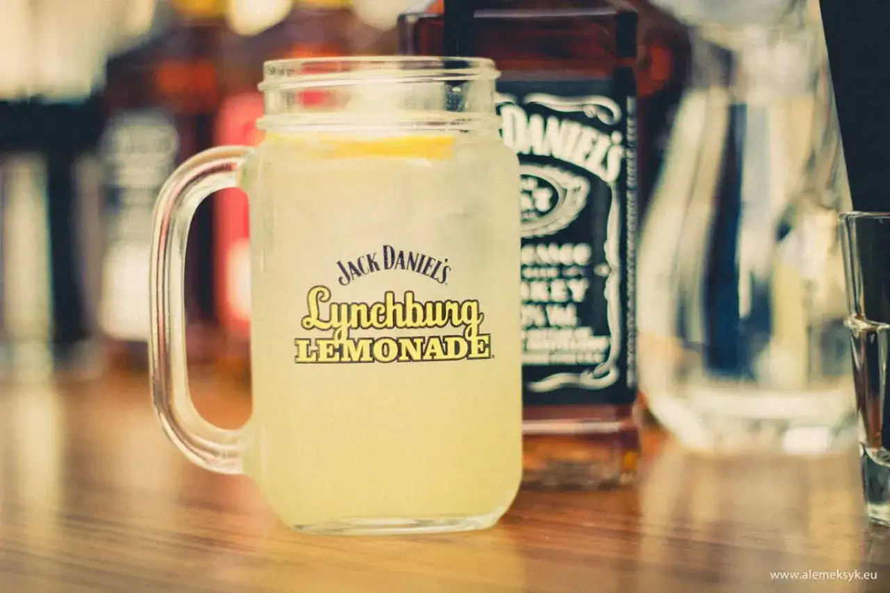 Orzeźwiająca Lynchburg Lemonade z Jack Daniel's w słoiku, obok butelki tego kultowego trunku. Idealne Jack Daniel's drinks na lato.