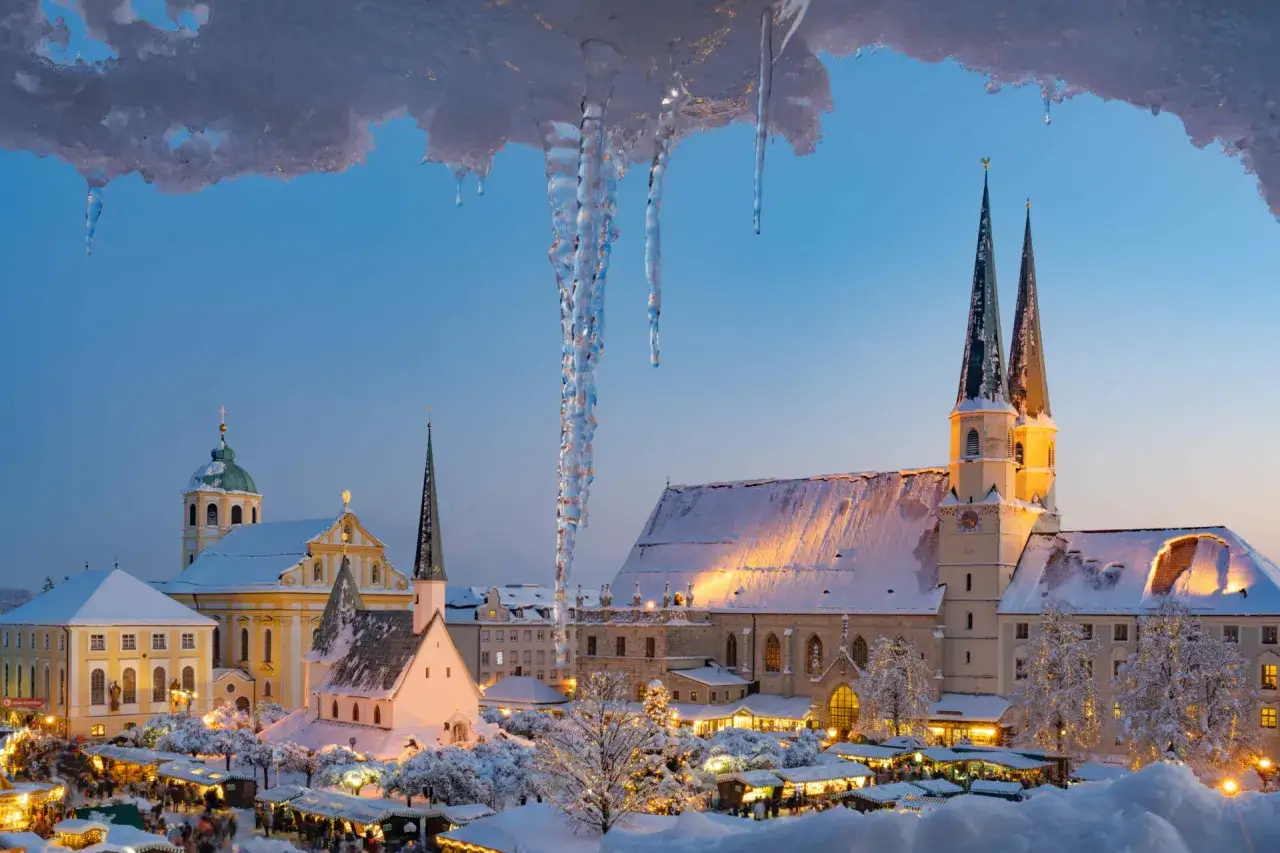 Eiszapfen h&auml;ngen &uuml;ber einem verschneiten Weihnachtsmarkt in Deutschland. Kirchen und beleuchtete St&auml;nde schaffen eine magische Winterstimmung.