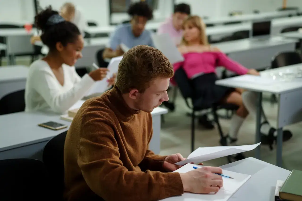 Studenci w sali wykładowej, zastanawiający się, czy bez matury ma się średnie wykształcenie.