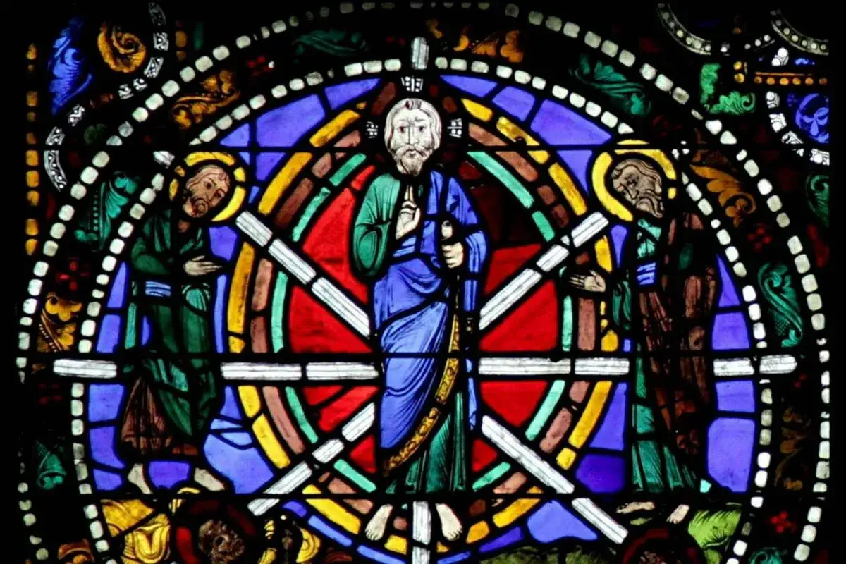 Stained glass window from Chartres Cathedral depicts three figures in vibrant colors. The central figure, a bearded man in blue, stands with a staff.
