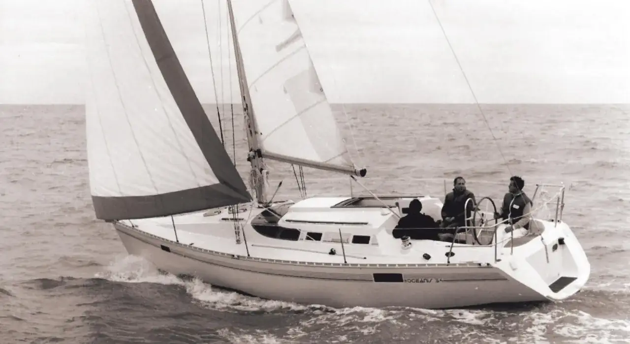 Barca a vela in navigazione, con tre persone a bordo. La prima 31.7 scheda tecnica &egrave; visibile sullo scafo.
