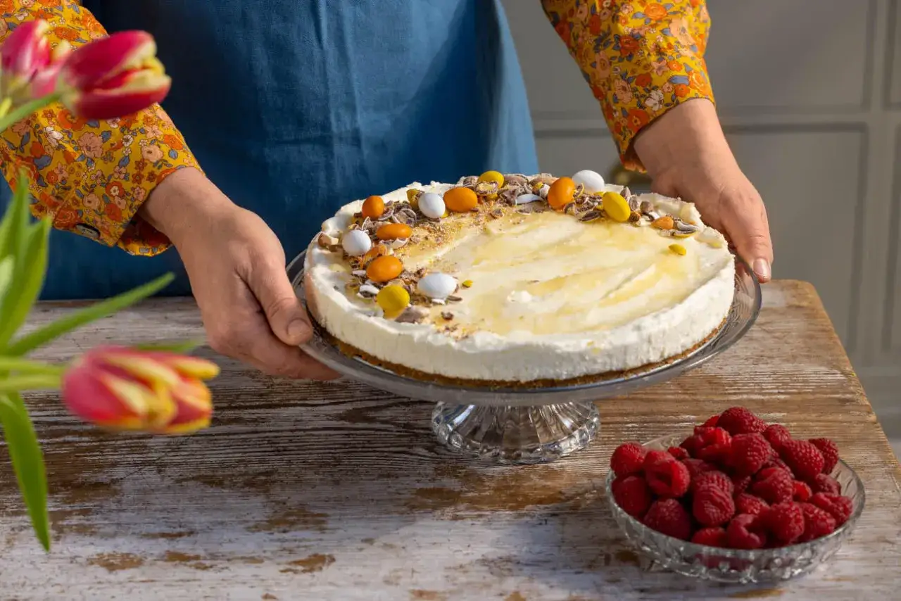 En krämig citron cheesecake med färgglada godisar och hallon på sidan.