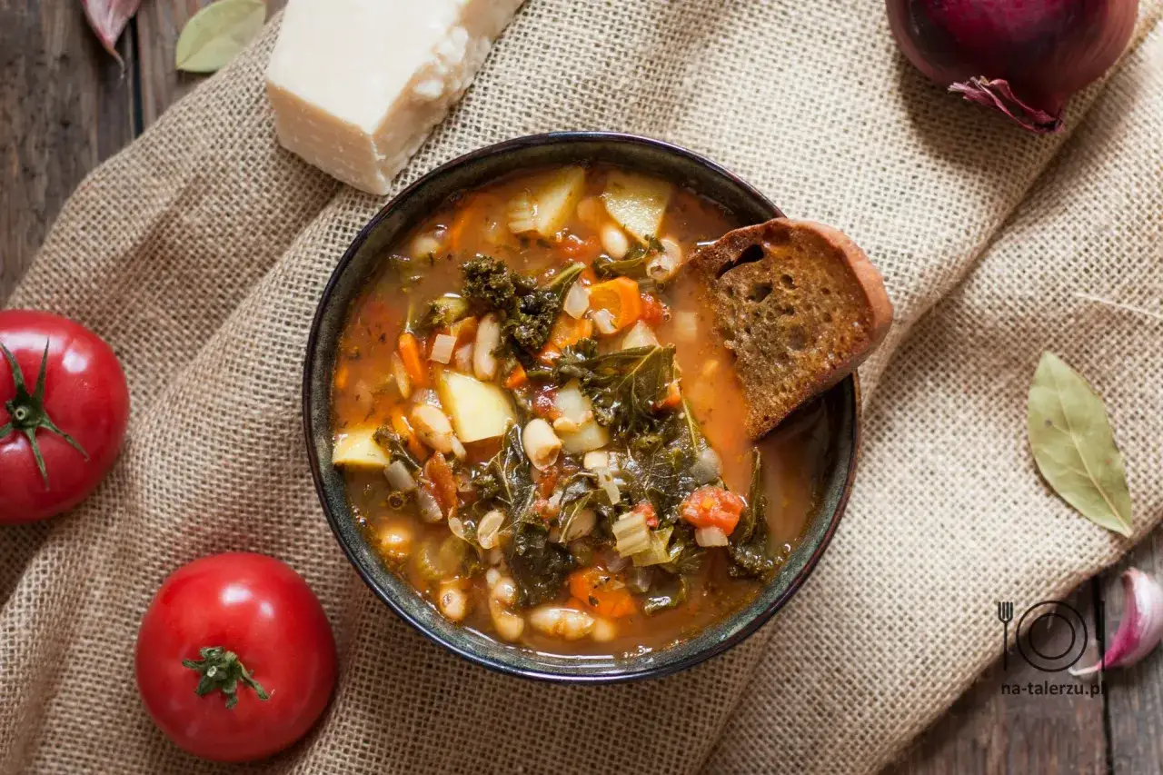 Zupa jarzynowa, czyli włoskie minestrone, pełna warzyw i fasoli, z grzanką. Obok pomidory, parmezan i czosnek.