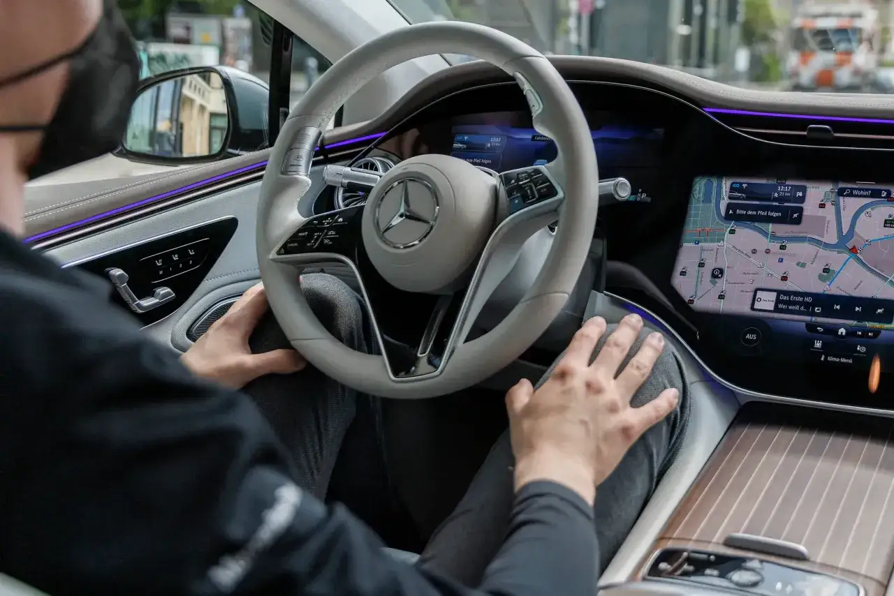 Intérieur d'une voiture électrique moderne. Le volant est tenu par un conducteur, le GPS affiche la route. Est-ce que les voitures électriques sont automatiques ? Pas encore, mais elles s'en rapprochent.