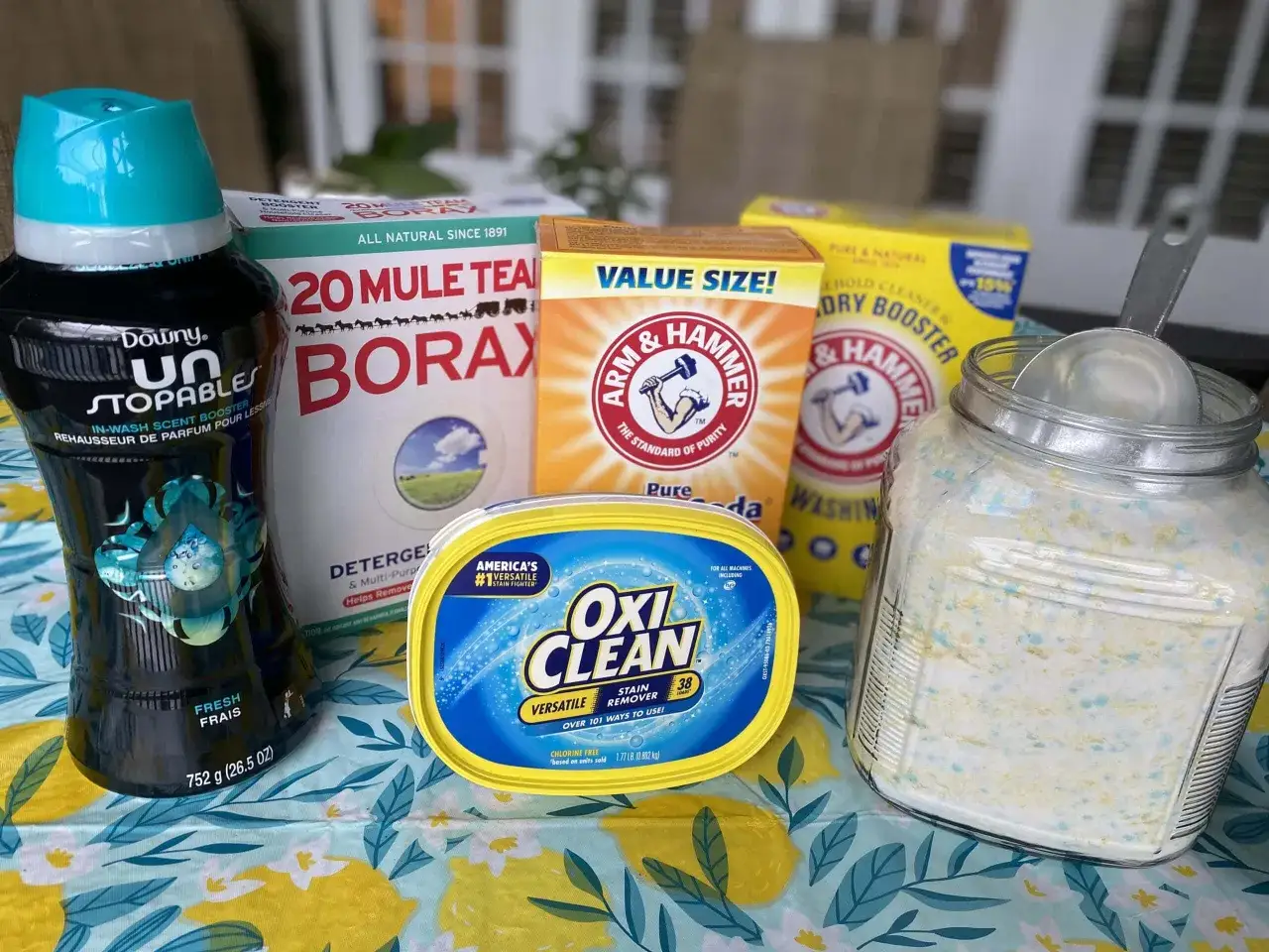Produits pour une lessive maison : Borax, bicarbonate de soude, OxiClean, assouplissant et une jarre de poudre.