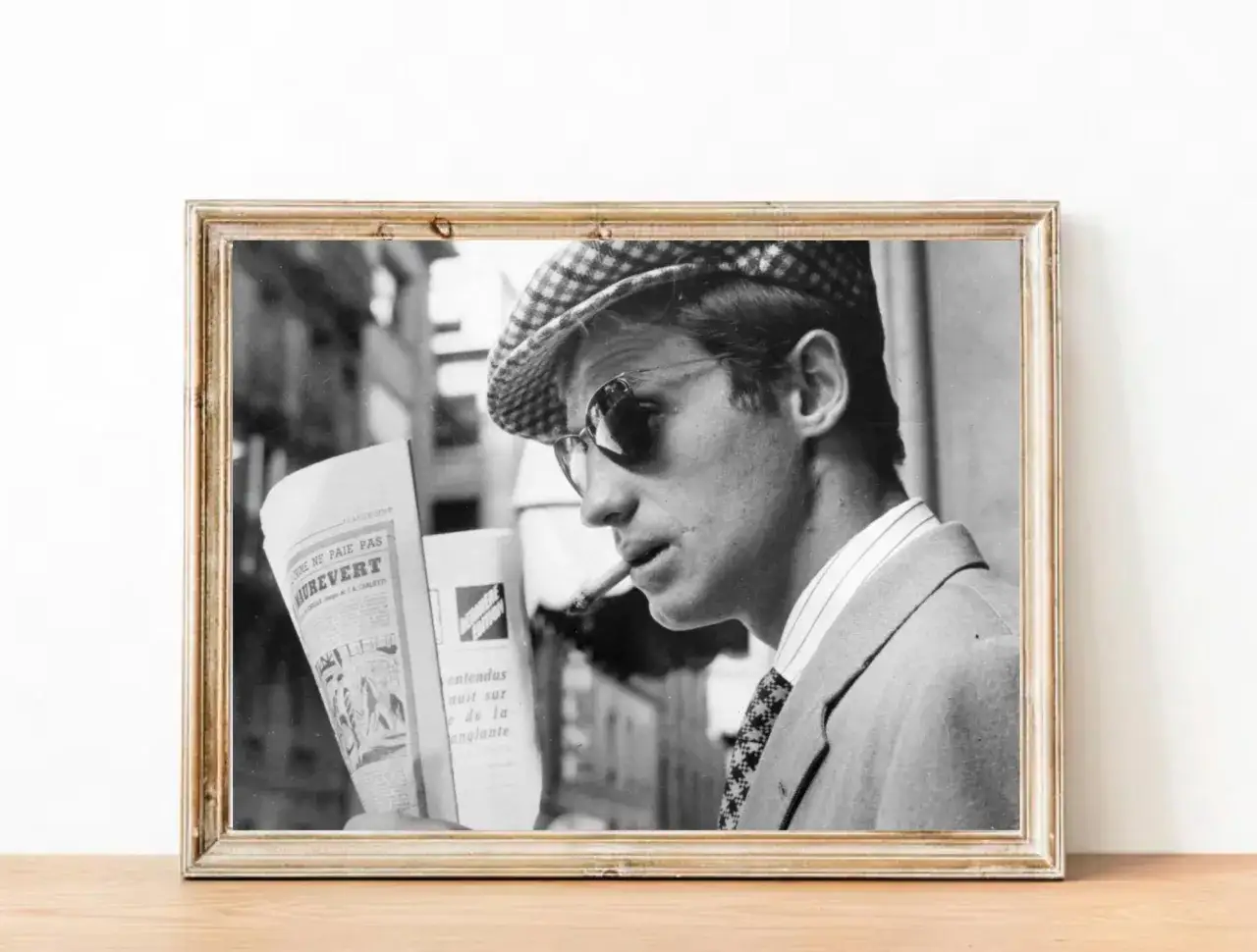 Jean-Paul Belmondo w beretce i okularach, z papierosem w ustach, czyta gazetę. Inspiracja dla wielu, jak jego **belmondo cytaty**.