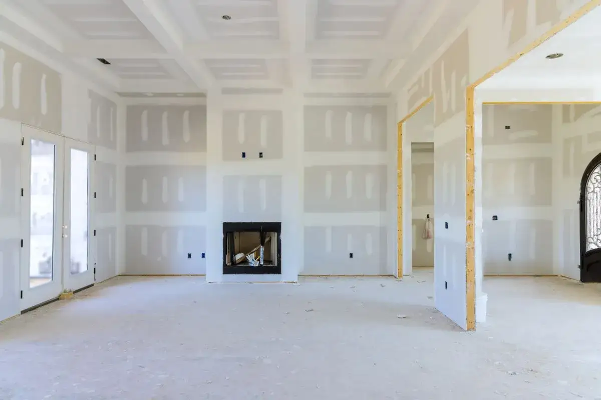 Interno in fase di finitura con pareti in cartongesso grezzo, camino e porte. Il pavimento è pronto per il cartongesso prima o dopo la posa.