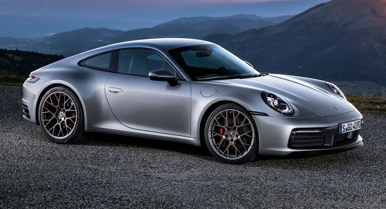 Srebrne Porsche 911 na tle górskich krajobrazów. Sprawdź aktualną porsche 911 cena i możliwości tego sportowego auta.