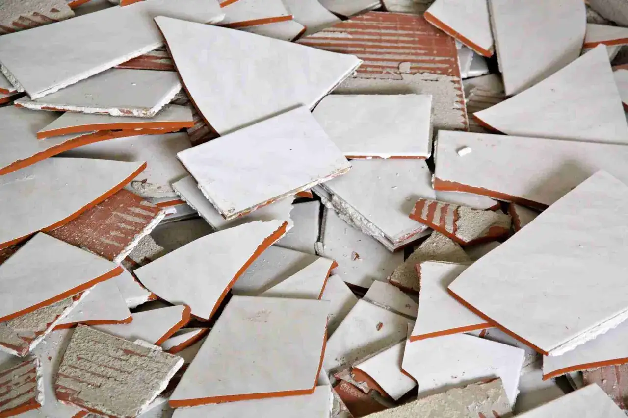 Tas de carreaux cassés, blancs et orangés, symbolisant un litige avec un artisan.