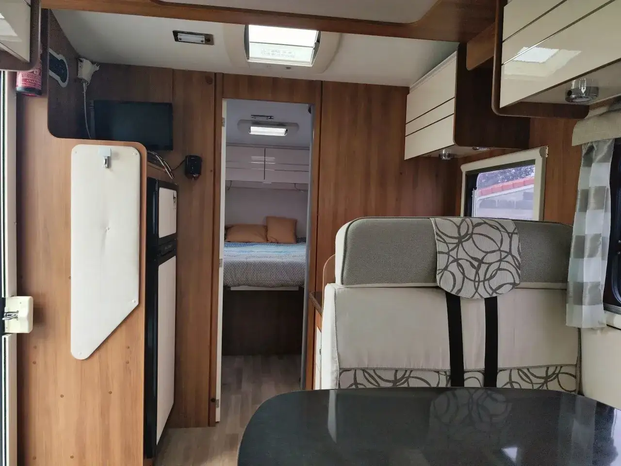 Intérieur d'un camping-car Rimor Katamarano 109 Plus. Lit, réfrigérateur et sièges confortables.