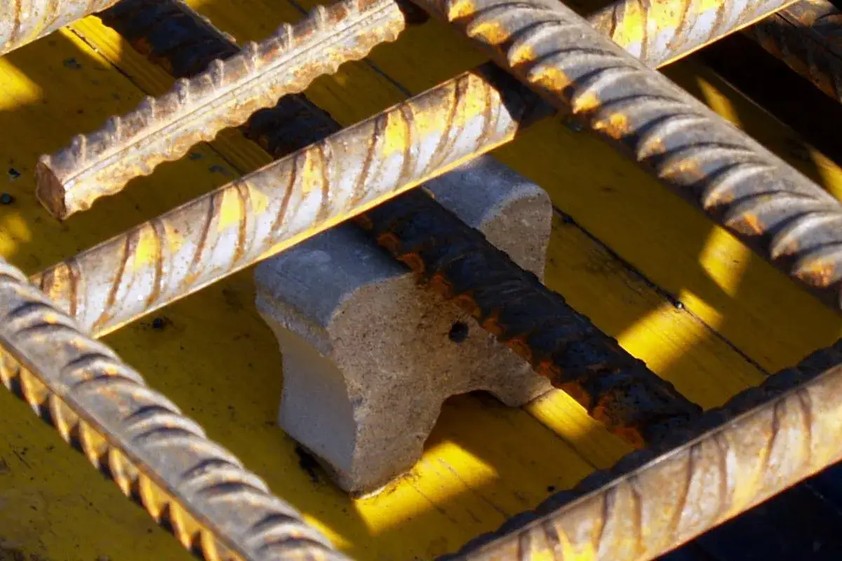 Betonstahl liegt auf gelber Schalung, gehalten von einem grauen Schalung Abstandhalter.