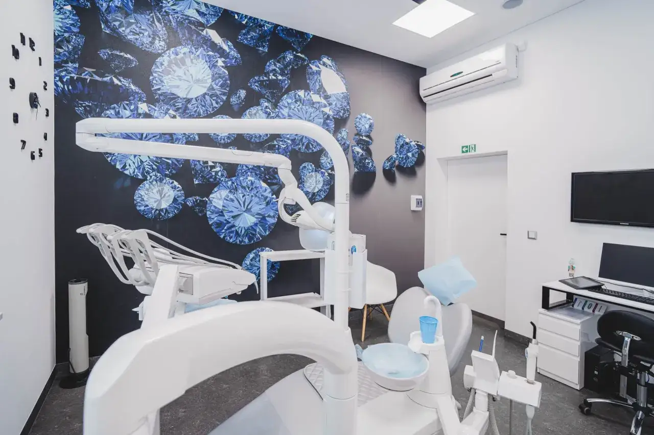 Nowoczesny gabinet stomatologiczny z fotelem dentystycznym i tapetą z niebieskimi diamentami.